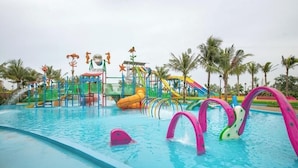 Un parque acuático con piscina, toboganes y estructuras de juego.