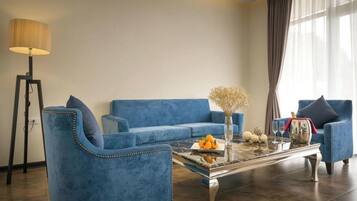 A modern living room with a blue sofa set, a glass coffee table, and a floor lamp.