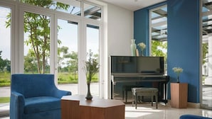Una sala de estar moderna con un piano, dos sillones azules y una mesa de centro.