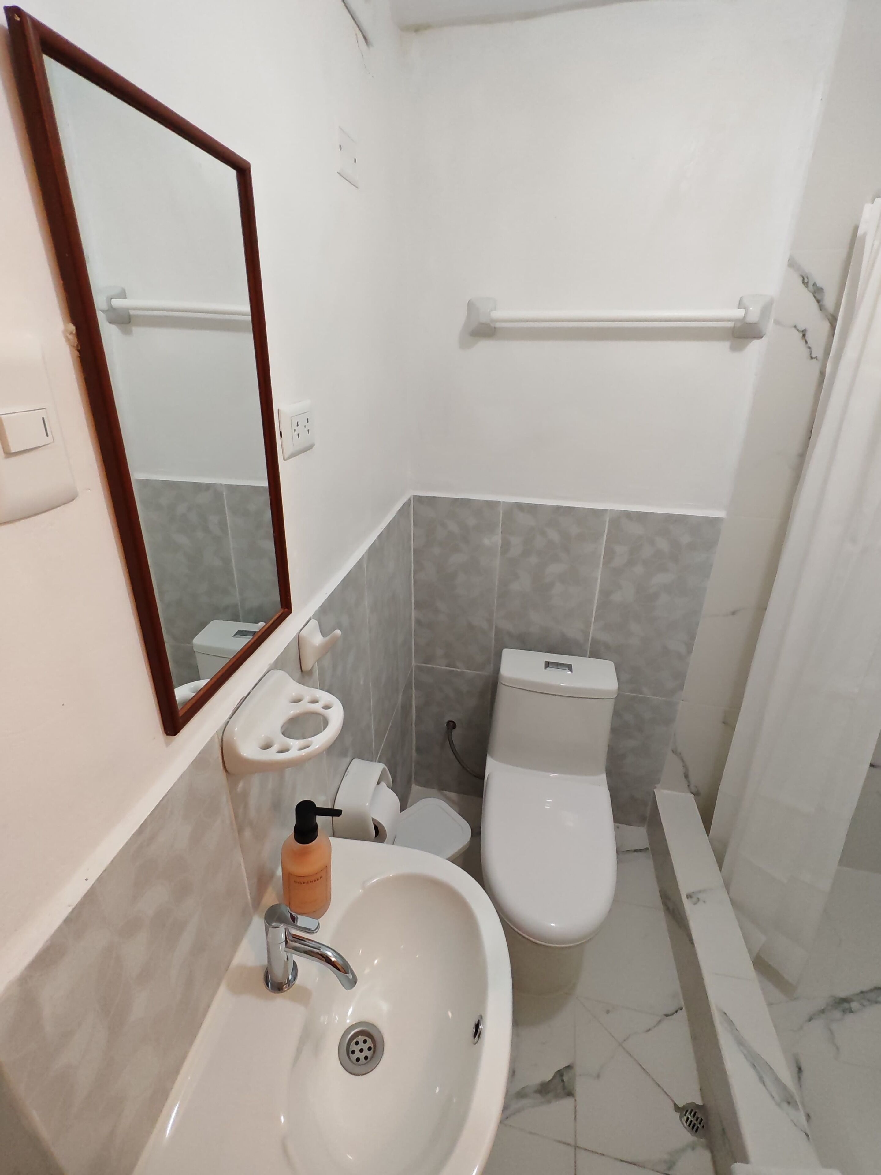 Un bagno con lavandino, specchio, water e vasca da bagno bianchi.