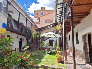 Un patio con escalones de piedra, plantas en macetas y mobiliario exterior.