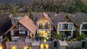 A resort with multiple bungalow-style buildings featuring thatched roofs, large windows, and a pool area. - Green Harmony Villa by Betterplace (Ubud)