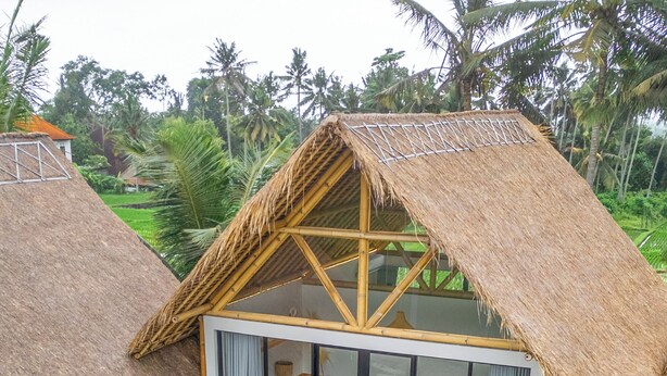 A two-story house with a thatched roof, a glass balcony, and a swimming pool. - Green Harmony Villa by Betterplace (Ubud)