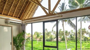 A bedroom with a large bed, a wooden ceiling, and a view of a lush green landscape through large windows. - Green Harmony Villa by Betterplace (Ubud)