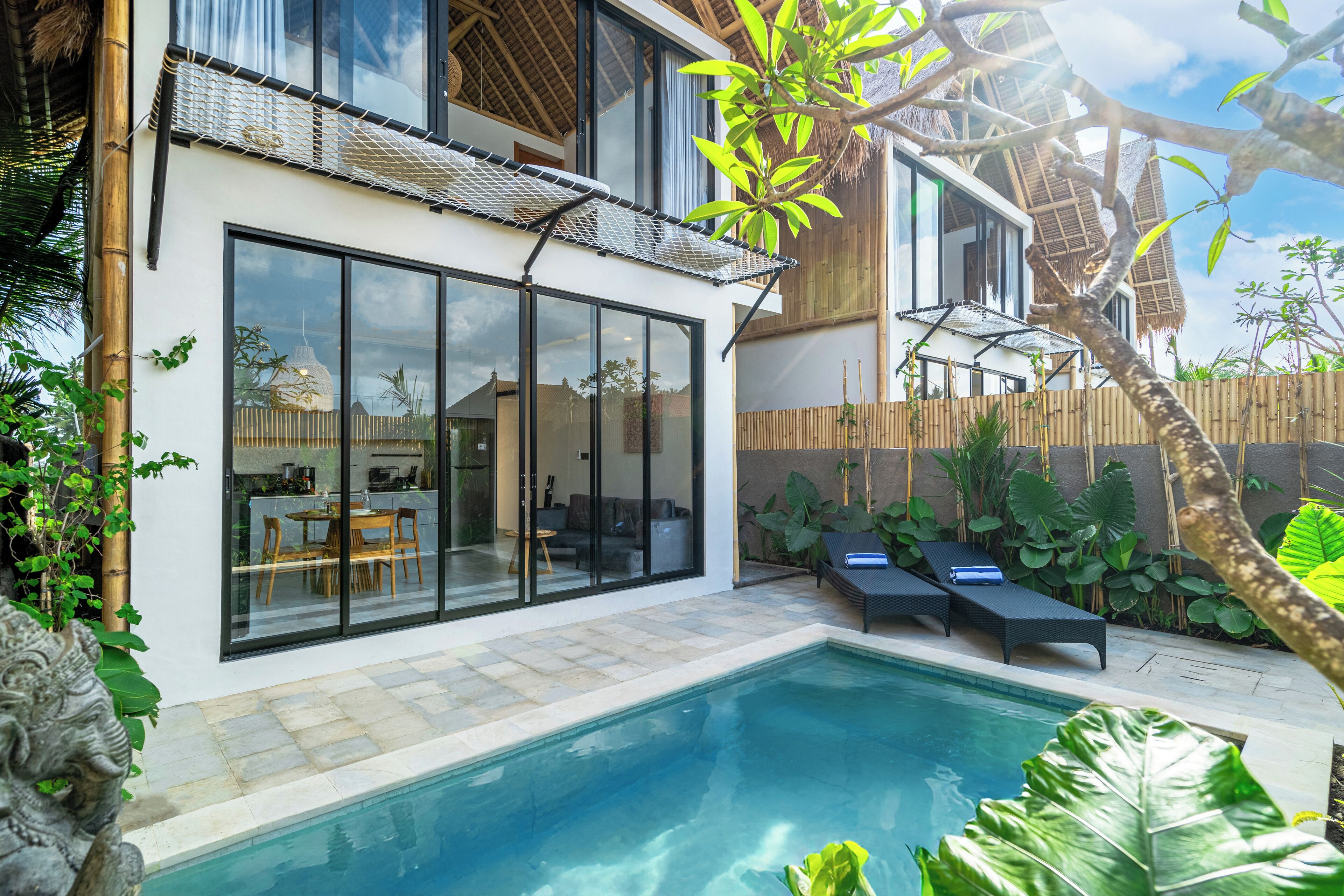 Una casa moderna con piscina, ventanas amplias y techo de paja.