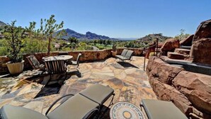 An outdoor patio with stone flooring, seating, and a view of mountains.