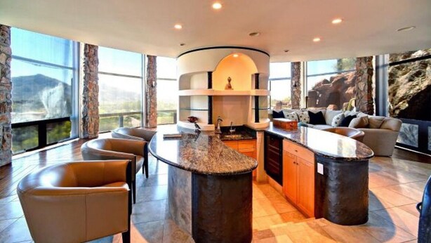 A modern kitchen with a central island, built-in appliances, and large windows offering a view of the outdoors.