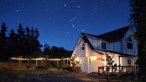 Una casa con porche, luces colgantes y un cielo nocturno estrellado.