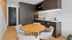 Une cuisine moderne avec des meubles de couleur bois foncé, un pare-feu en carreaux blancs et une table ronde en bois, accompagnée de quatre chaises.