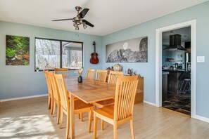Un coin repas avec une table et des chaises en bois, un ventilateur de plafond et des œuvres d’art accrochées aux murs.
