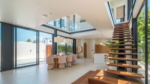 A spacious interior with a modern staircase, large windows, and a dining area. - Villa Maverick (Canggu)