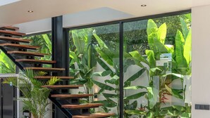 A modern staircase with wooden steps and black railings, leading to a glass door. - Villa Maverick (Canggu)