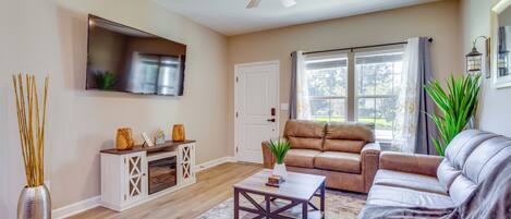 A living room with a ceiling fan, a flat-screen TV, a sofa, a coffee table, and a fireplace.