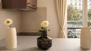 A kitchen with a window, a wooden cabinet, and two vases with flowers.