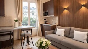 Un appartement moderne comprenant un coin repas, une kitchenette, un canapé et une grande fenêtre.