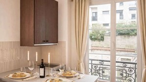 Un coin repas avec une table dressée pour quatre personnes, des bougies et une bouteille de vin.