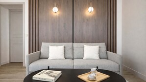 A modern living room with a grey sofa, a black coffee table, and two wall-mounted light fixtures.
