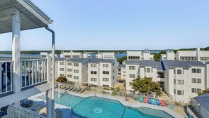 A pool area with a view of multiple buildings, a clear sky, and a body of water in the background.