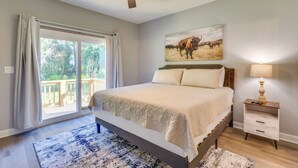A bedroom with a large bed, a ceiling fan, a nightstand with a lamp, and a painting of cattle on the wall. - 1 Mi to Florida State Capitol: Tallahassee Escape (Tallahassee)