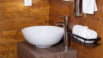 Un baño con un lavamanos blanco de diseño, un grifo cromado, un perchero y paneles de madera.