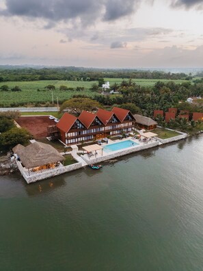 A large building with multiple rooms, a swimming pool, and a dock extending into a body of water. - Riverside Hotel Chachalacas (Úrsulo Galván)