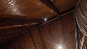 A cozy attic bedroom with a wooden ceiling, a large bed, a sofa, and a coffee table.