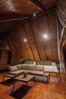 Un dormitorio acogedor en el ático, con techo de madera, una cama grande, un sofá y una mesa de centro.