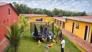 Ein Innenhof mit Trampolin, Palmen und gelben Gebäuden.