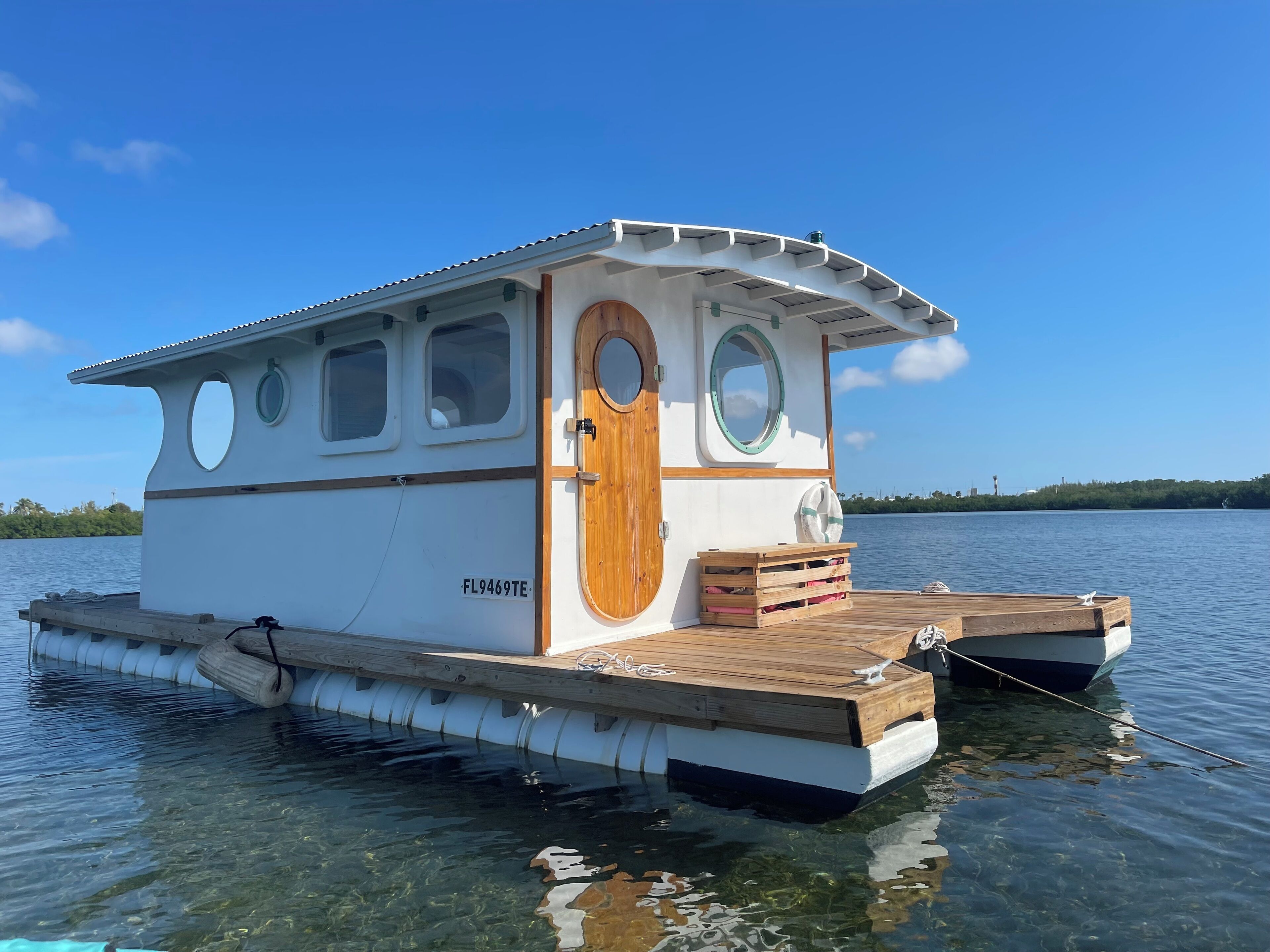 A houseboat with a wooden deck, a door, and windows.