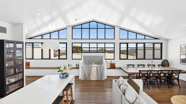 A spacious kitchen with large windows, a dining area with a wooden table and chairs, and a cozy seating area with a sofa. - Luxurious Beach House with Breath-taking Views (Ocean Grove)