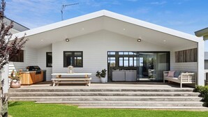 A modern house with a covered patio, a barbecue area, and a glass door entrance. - Luxurious Beach House with Breath-taking Views (Ocean Grove)