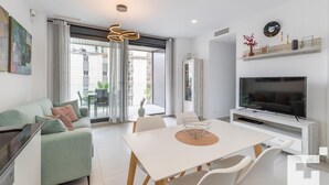 A modern living room with a sofa, dining table, chairs, a TV, and a large window. - Calpe Beach II 3C - Grupo Turis - Calpe, Costa Blanca (Calpe)