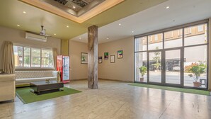 Un hall d’entrée spacieux avec une grande fenêtre, un canapé, une table basse et une colonne.