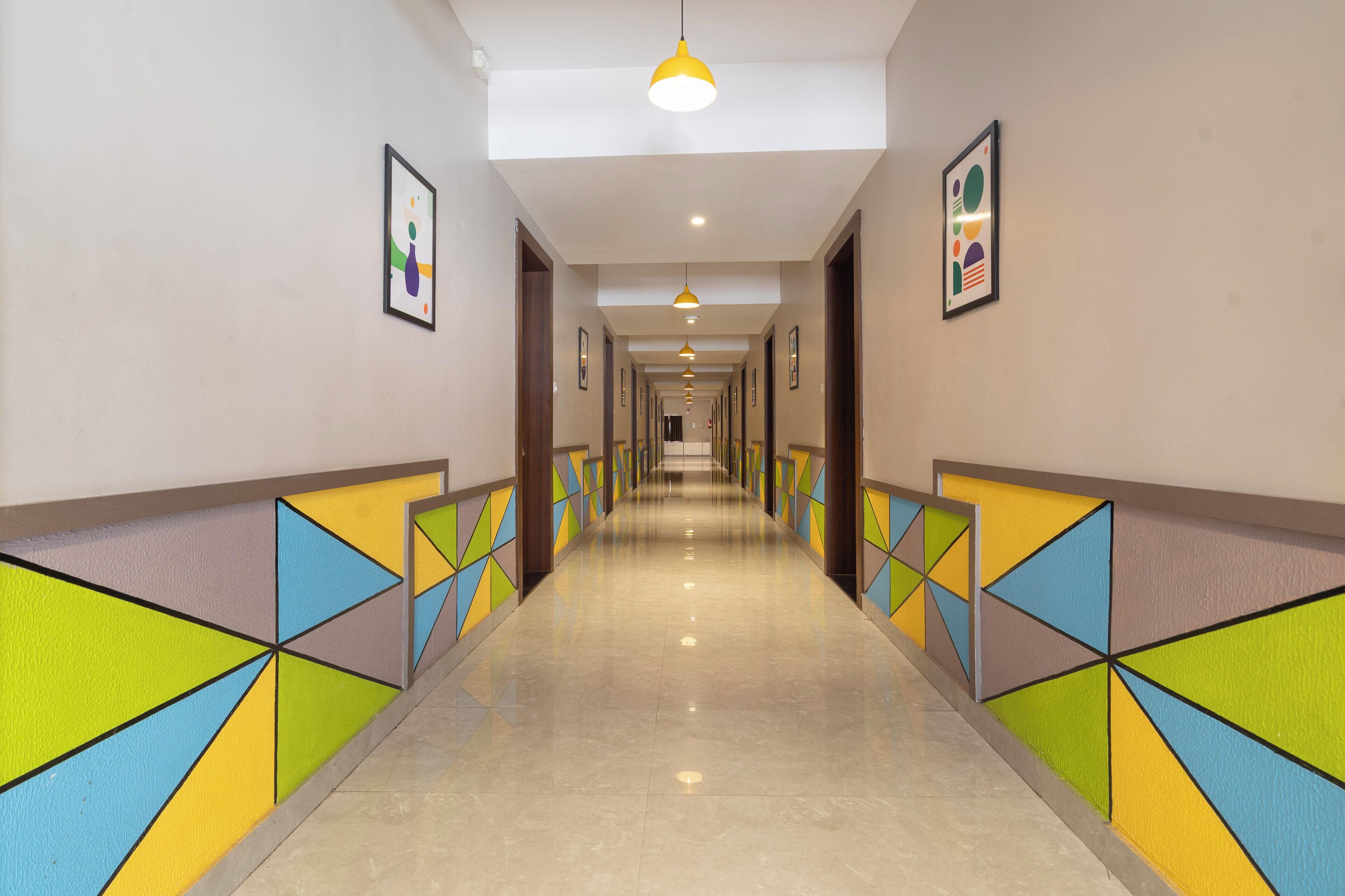 A long, well-lit hallway with geometric wall designs and framed artwork.