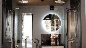 Een moderne badkamer met een glazen douchecabine, een ronde spiegel en een houten wastafelmeubel.
