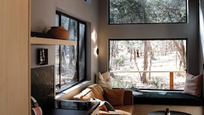 Een moderne woonkamer met een ingebouwde bank, grote ramen en een hoofdbord met een visgraatmotief.