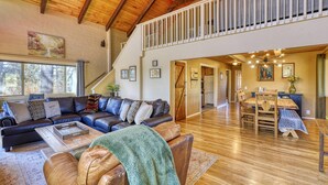 A spacious living room with a large sectional sofa, a dining area with a wooden table and chairs, and a staircase leading to an upper level.