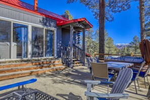 Eine Lodge mit rotem Dach, einer Holzterrasse und einer Sitzgelegenheit im Freien mit Stühlen und Tisch.