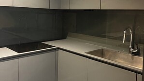 Une cuisine moderne avec des meubles gris, un évier en acier inoxydable et un plan de travail noir.