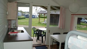 A compact kitchenette with a sink and a small table, a dining area with chairs, and a view of the outside. - 2 Person Holiday Park Home in Jelling (Jelling)