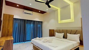 A modern bedroom with a large bed, a ceiling fan, and a built-in air conditioning unit. - The Breeze Valley (Jaoli)