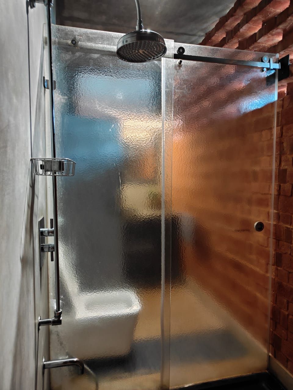 A glass-enclosed shower stall with a metal frame and a showerhead.