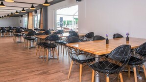 Un grand espace dédié à la salle à manger, avec de longues tables en bois et des chaises à structure métallique noire.