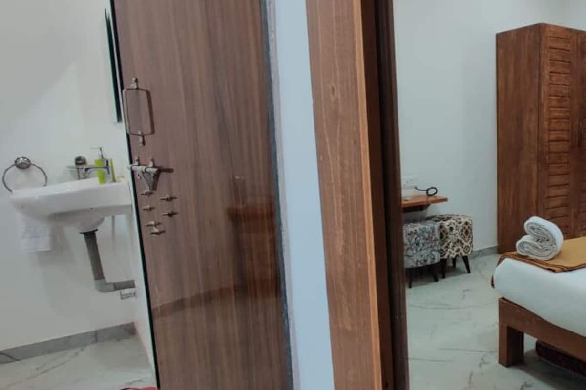 Ein Schlafzimmer mit einem Bett, einem Holzschrank, einem kleinen Tisch mit Stuhl und einem Fenster mit Vorhängen.