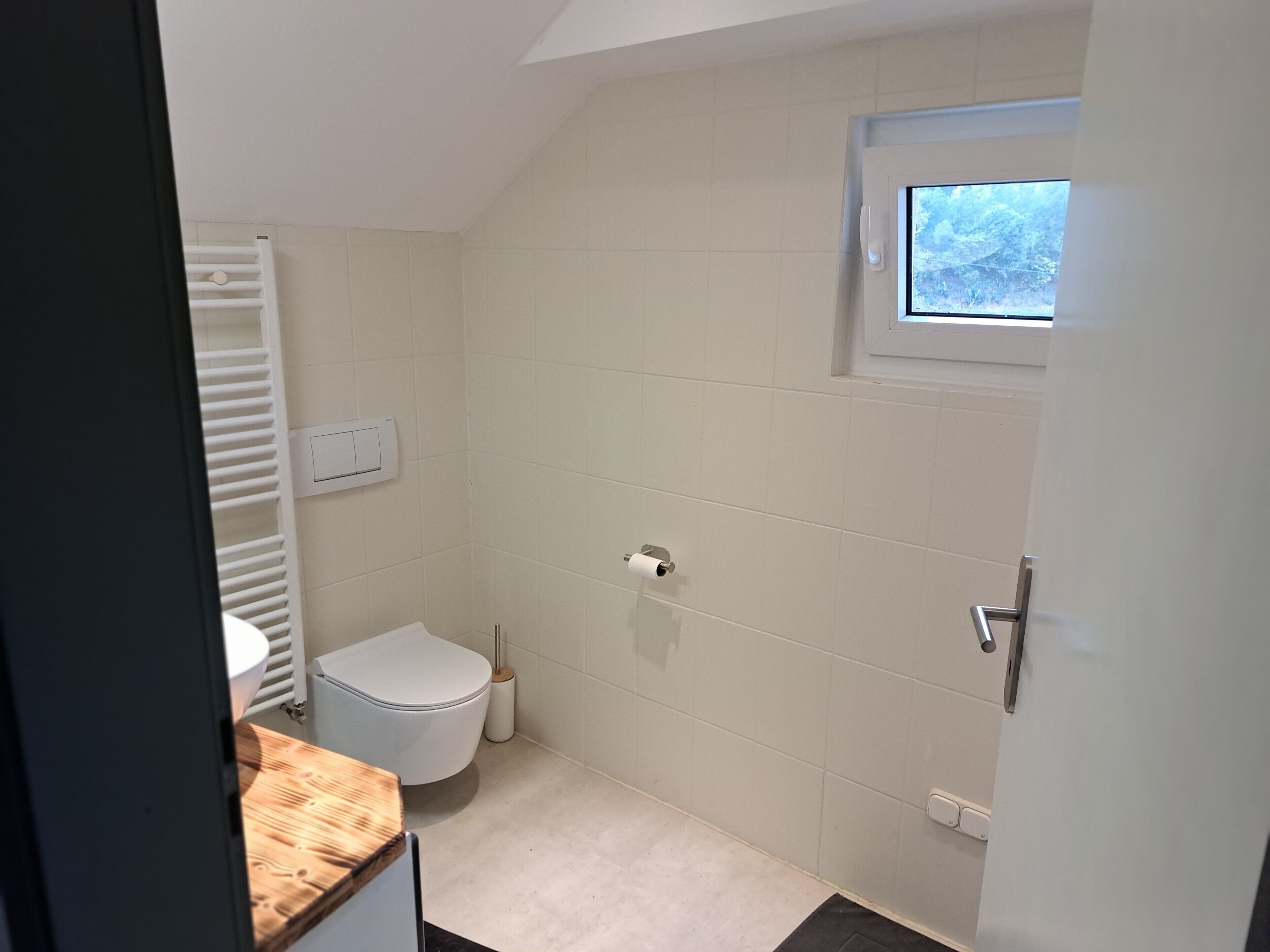 A small, clean bathroom with a toilet, a sink, and a window.