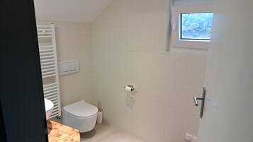 A small, clean bathroom with a toilet, a sink, and a window.