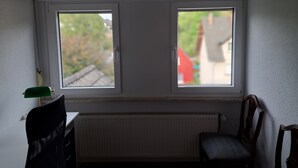 A room with two windows, a radiator, a desk, and a chair. - 'Room near Nürburgring' with shared garden and Wi-Fi (Müsch)