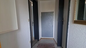 A narrow hallway with a striped rug, a door at the end, and a light switch on the wall. - 'Room near Nürburgring' with shared garden and Wi-Fi (Müsch)