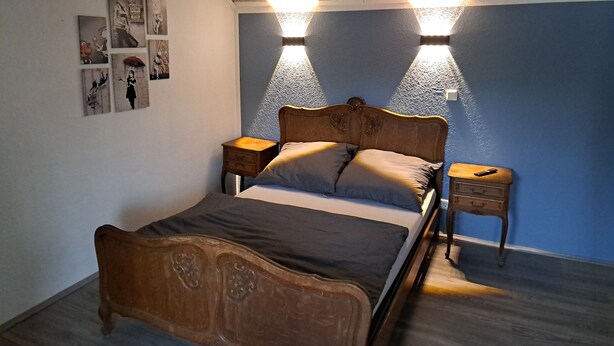 A bedroom with a wooden bed, two bedside tables, and wall-mounted lights. - 'Room near Nürburgring' with shared garden and Wi-Fi (Müsch)
