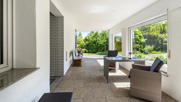 A modern outdoor patio with a table and chairs, a bench, and a view of greenery. - Holiday Apartment 'Auszeit Sauerland' with Private Terrace and Garden (Meinerzhagen)